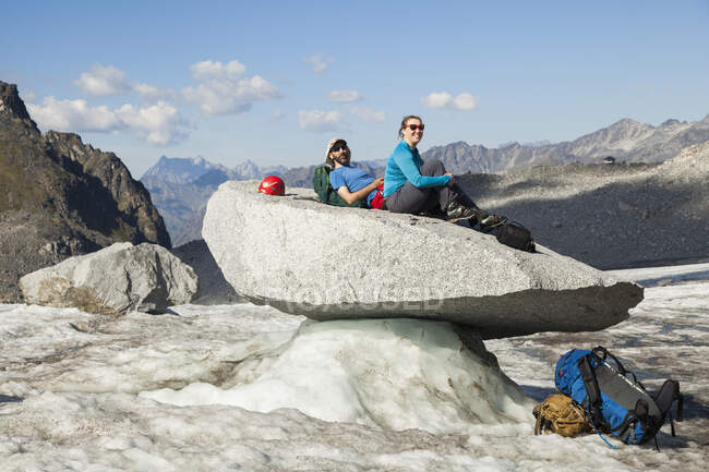 Pareja sentada en roca, Glaciar Snowbird, Montañas Talkeetna, Alaska - foto de stock