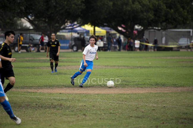 Teen soccer player dribbling the ball during a game — Stock Photo