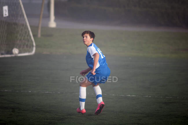 Giocatore di calcio adolescente pronto a difendersi su un campo nebbioso — Foto stock