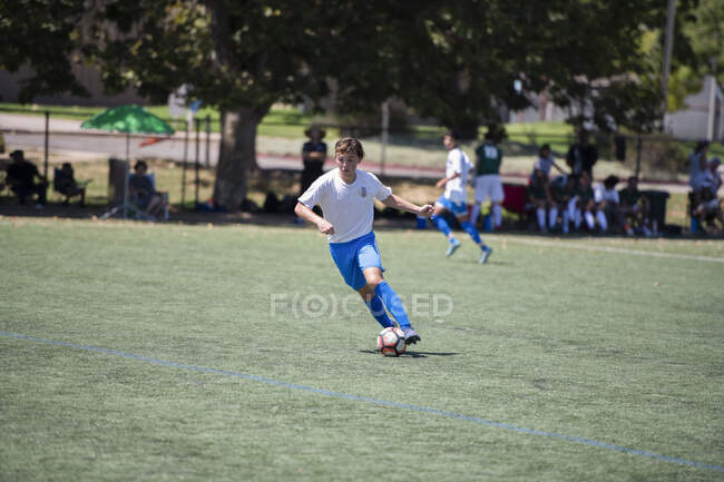 Giocatore di calcio adolescente dribbling la palla durante una partita — Foto stock