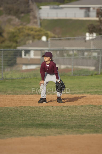 Piccolo ragazzo baseball League in posizione pronta nel campo interno — Foto stock