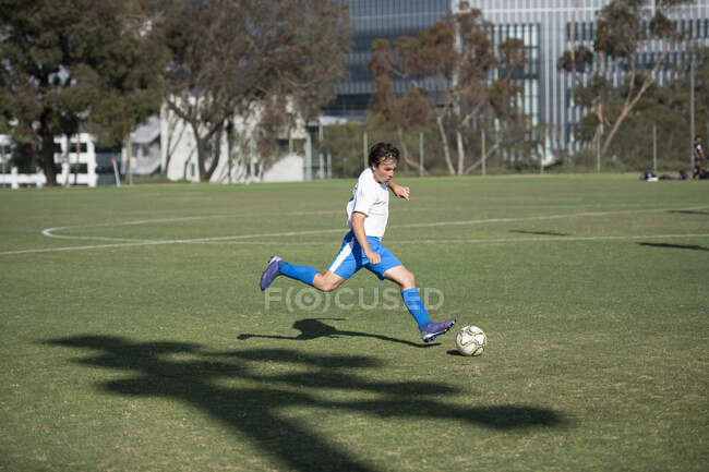 Giocatore di calcio adolescente in procinto di colpire la palla su un calcio libero — Foto stock