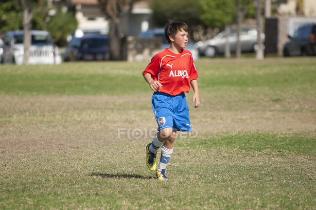 Jogging jovem jogador de futebol no campo durante um jogo — Fotografia de Stock