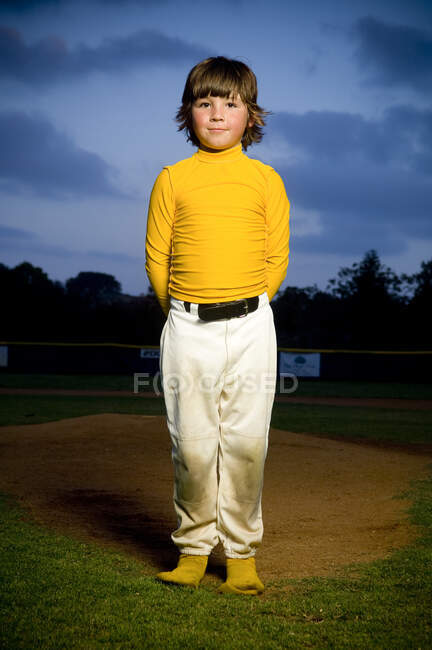 Portrait of a young boy in deshevled yellow and white baseball uniform — Stock Photo