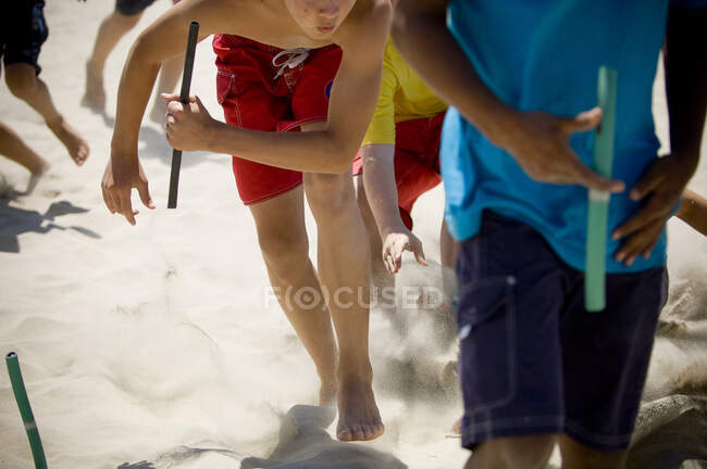 Close-up of junior lifegaurd grabbing a tube in a game of beach flags — Stock Photo