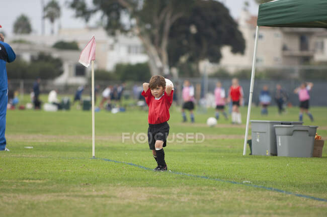 Молодий хлопчина збирається кинути на футбольне поле. — стокове фото