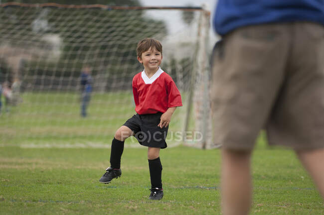 Мальчик с большой улыбкой на футбольном поле — стоковое фото