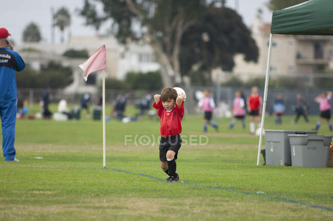 Молодой футболист, пытающийся бросить мяч — стоковое фото