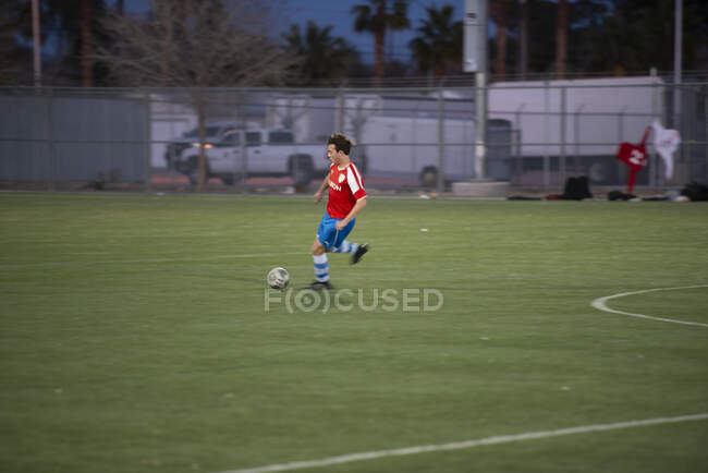 Підліток - футболіст під час гри бігає по м 