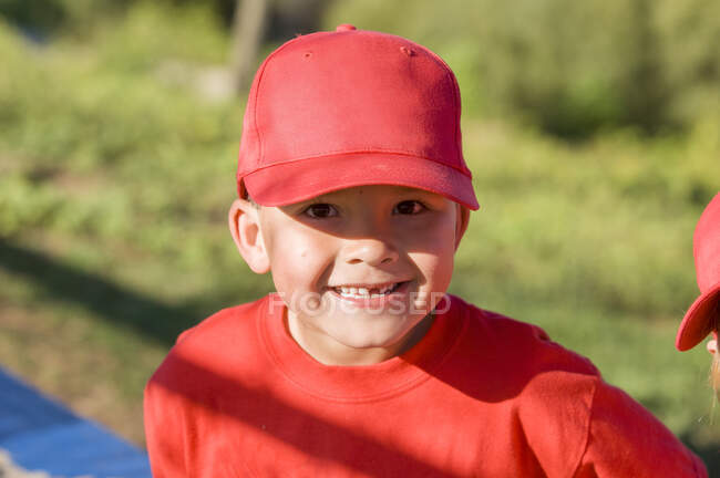 Giovane ragazzo manca un dente in berretto da baseball rosso sorridente alla fotocamera — Foto stock