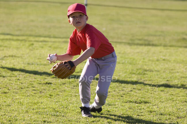 Мальчик играет в бейсбол во время игры TBall — стоковое фото