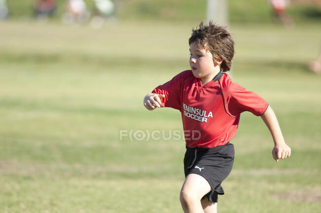 Молодий футболіст бігає по полю під час гри. — стокове фото