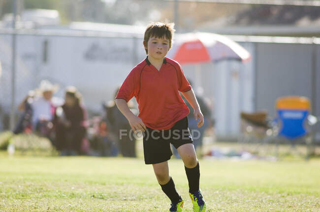 Jeune garçon se concentrant sur un terrain de football — Photo de stock