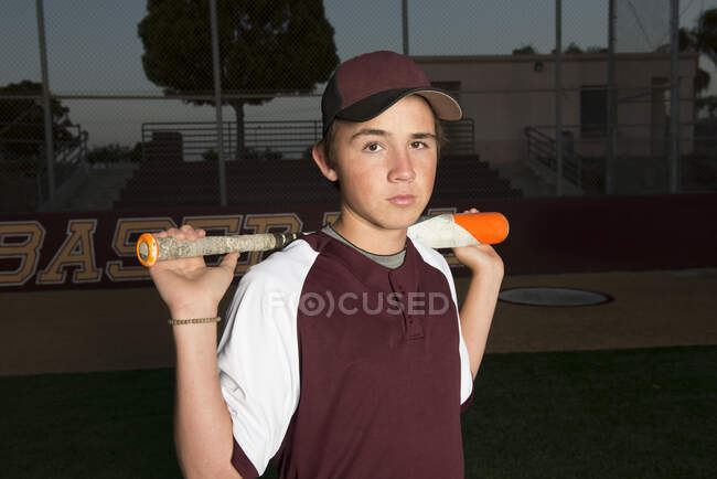 Porträt eines Baseballspielers der High School in kastanienbrauner Uniform, der seinen Schläger hält — Stockfoto