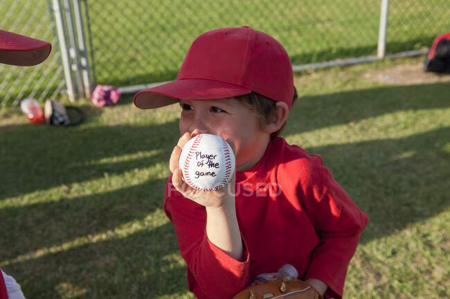 Young boy holding his player of the game baseball on the TBall field — Stock Photo