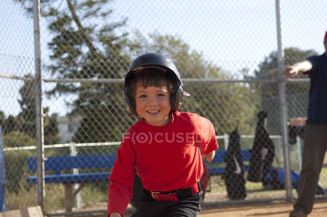Jovem no capacete de beisebol com grande sorriso no campo TBall — Fotografia de Stock