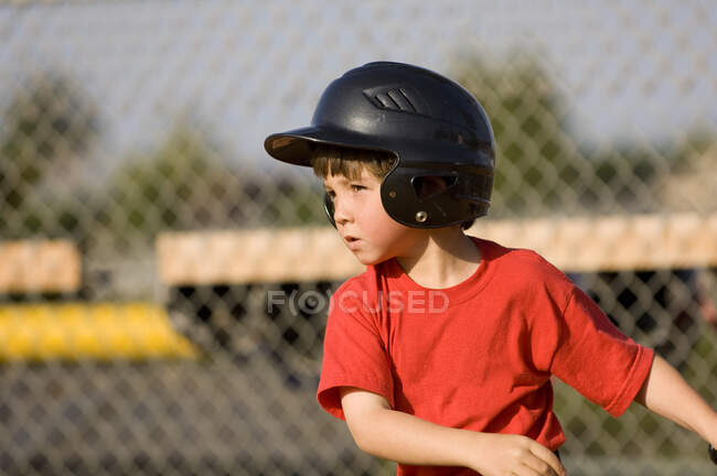 Молодий хлопчик в бейсбольному шоломі зосередився на своєму хіті — стокове фото