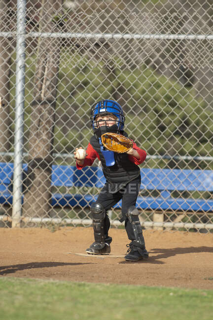 Young boy in catchers gear waiting at home plate to tag out a runner — Stock Photo
