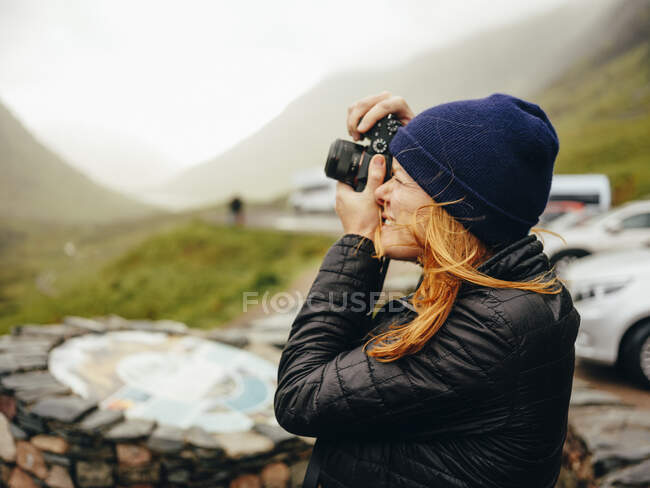 Mujer fotografiando a Tres Hermanas de Glencoe, en un día húmedo - foto de stock