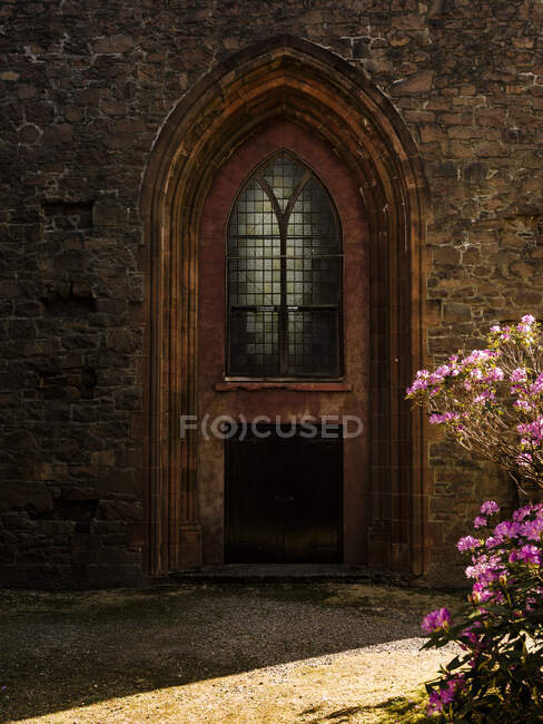 Porta da igreja com um arbusto de rododendro na frente — Fotografia de Stock