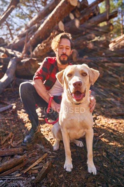 Ritratto di giovane uomo tatuato con il suo cane nella foresta — Foto stock