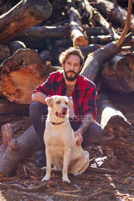 Портрет молодого татуированного человека с собакой в лесу — стоковое фото