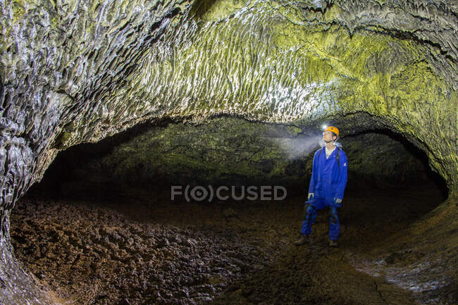 Uno scienziato ammira i microbi gialli sul soffitto di una caverna di tubo di lava — Foto stock
