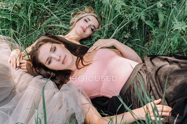 Duas meninas bonitas estão deitadas na grama — Fotografia de Stock