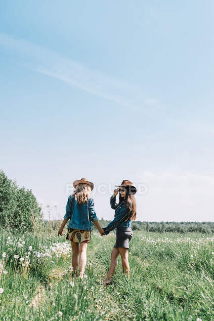 Dos chicas con sombreros en el campo - foto de stock