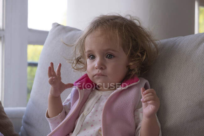 Маленькая девочка сконцентрировалась смотреть телевизор одна в своей гостиной. — стоковое фото