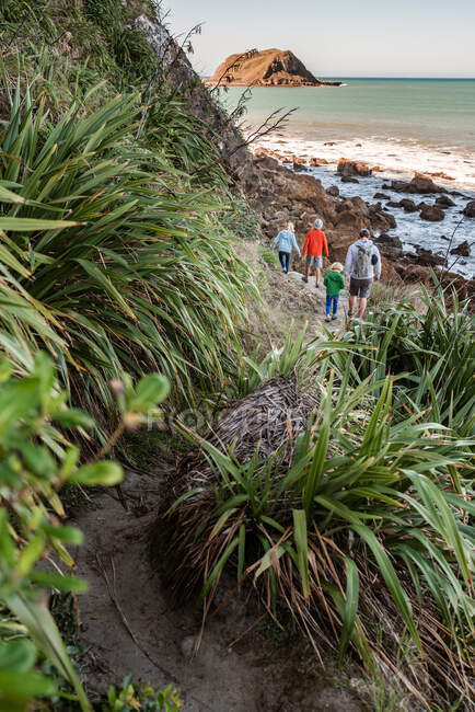 Padre e hijos caminando cerca del océano en Nueva Zelanda - foto de stock