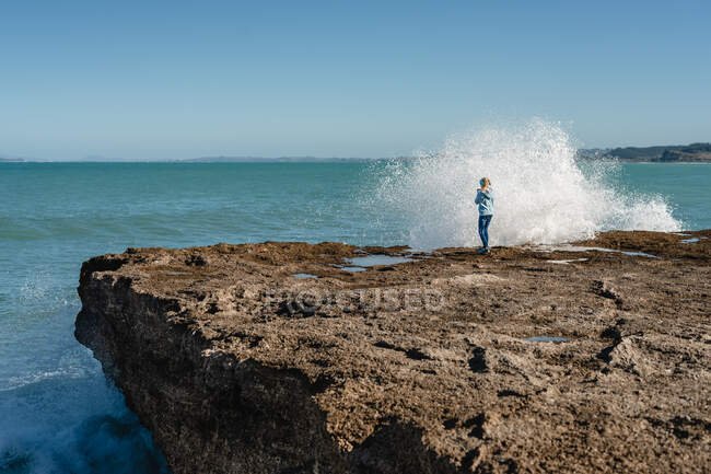 Tween menina de pé em um penhasco com vista para o oceano — Fotografia de Stock