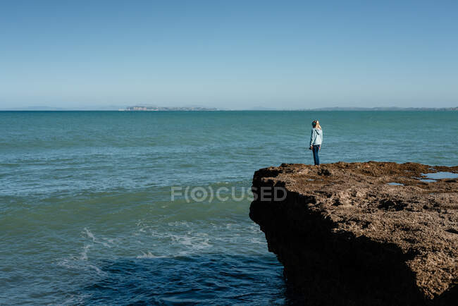 Tween menina de pé em um penhasco com vista para o oceano — Fotografia de Stock