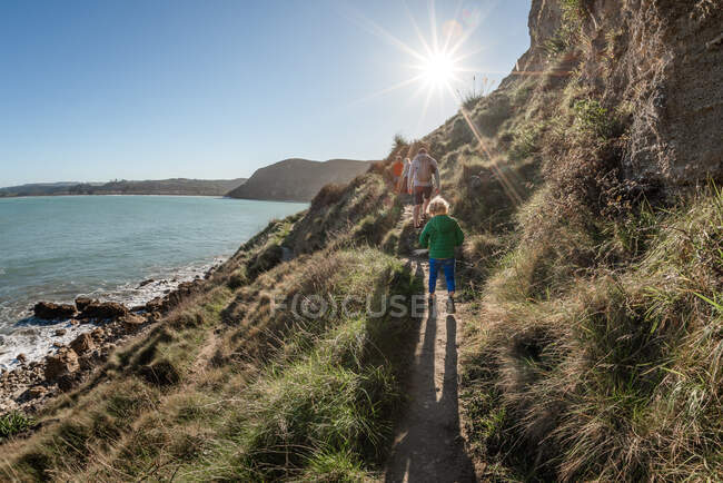 Father and kids hiking on seaside mountain path in New Zealand — Stock Photo