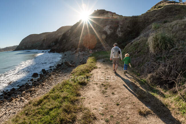 Father and son walking on a mountain path above the ocean in New Zealand — Stock Photo