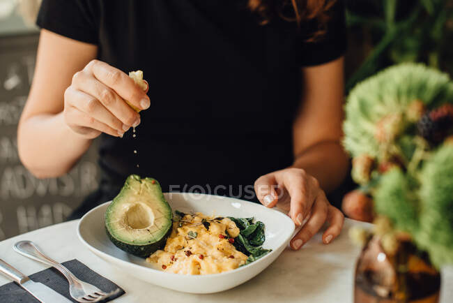 Mujer comiendo ensalada con verduras y frutas frescas - foto de stock