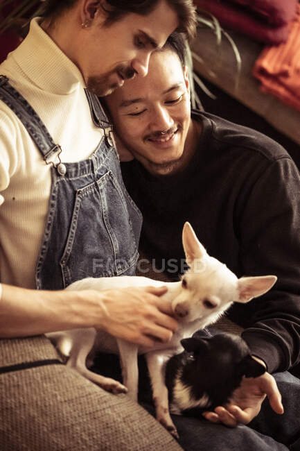 Gay male interracial couple relaxing with dog at home — Stock Photo