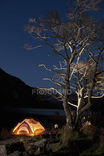 Caminhante do sexo feminino sentado fora de sua tenda no acampamento no norte do País de Gales — Fotografia de Stock