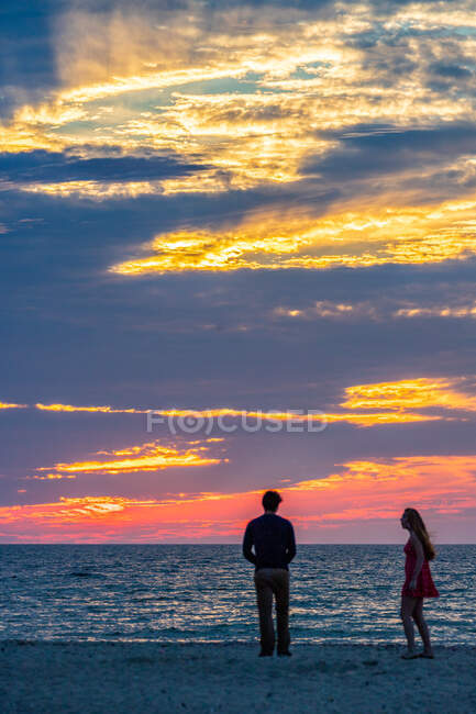 Jeune couple sur la plage pendant le beau coucher de soleil d'été. — Photo de stock