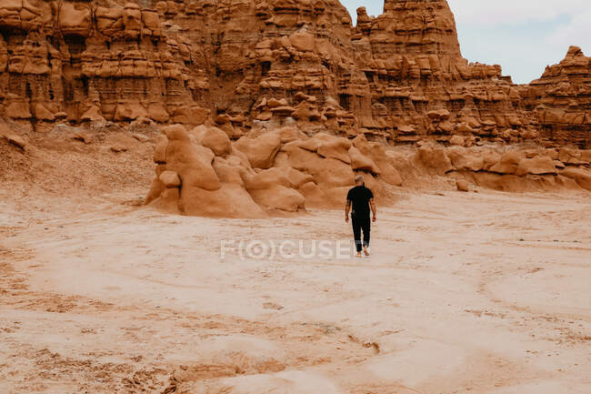 Hombre caminando solo entre rocas hoodoo en Goblin Valley - foto de stock
