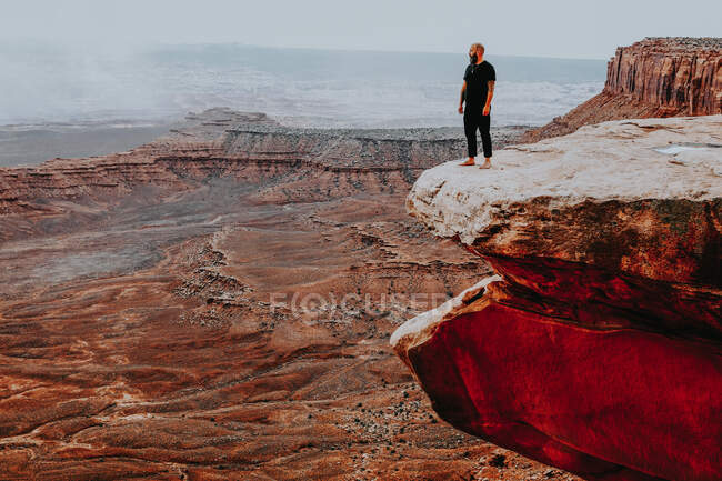Uomo in piedi sul bordo di una grande scogliera con vista aperta — Foto stock