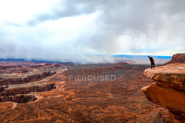 Людина дивиться над каньйонами на краю великої скелі — стокове фото