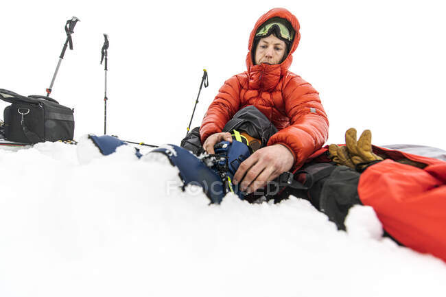 Low angle of man putting his ski boots on in the middle of the snow — Stock Photo