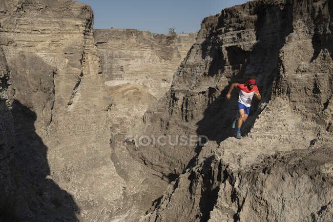 A man trail running down on technical terrain leaving dust on his way — Stock Photo