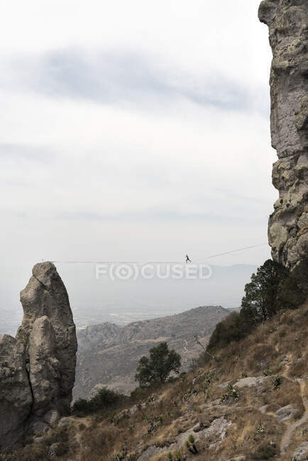 Una persona posa balanceándose en lo alto de Los Frailes - foto de stock