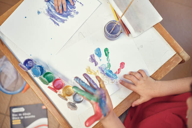 Ausgeschnittene Ansicht weiblicher Hände, die Papier mit Farbe und Zeichnung auf Leinwand halten — Stockfoto