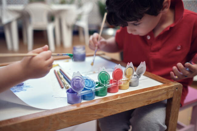 Crianças brincando em um pátio interior e pintura com tintas de água — Fotografia de Stock