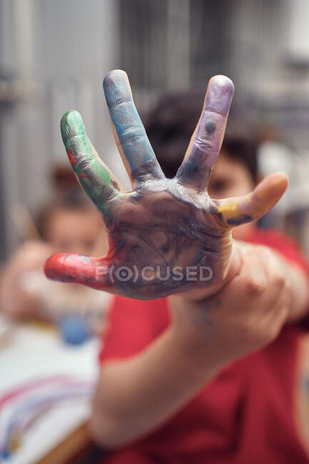 Мальчик показывает раскрашенную в акварель руку, играя с сестрой — стоковое фото