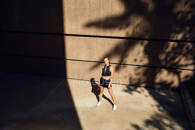 Portrait of beautiful young woman in stylish modern sportswear posing on city street — Stock Photo