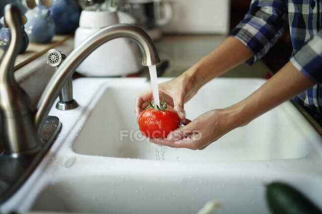 Primo piano delle mani della donna che lava un pomodoro — Foto stock